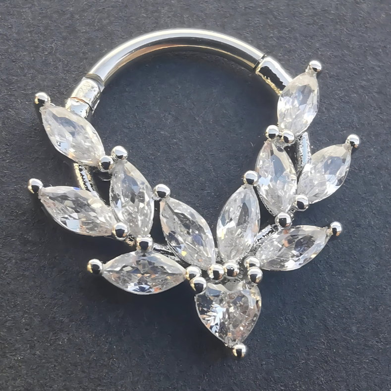 Close‑up of a 16 gauge silver septum and daith clicker ring with sparkling cubic zirconia stones, made from 316L surgical steel.