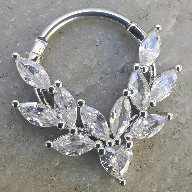 Close‑up of a 16 gauge silver septum and daith clicker ring with sparkling cubic zirconia stones, crafted from 316L surgical steel.