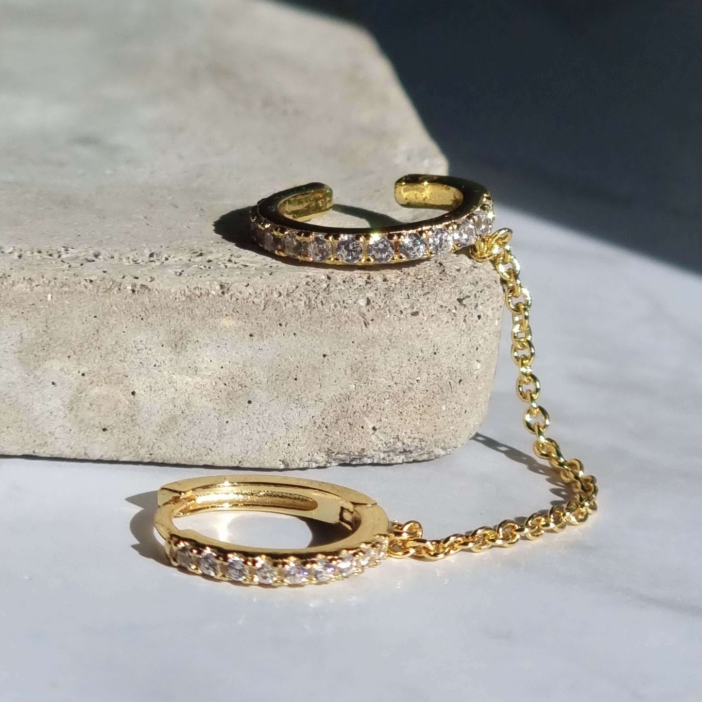Hoop to cuff chain ear piercing featuring a brilliant white zirconia stone set in 18K gold-plated 925 sterling silver with a sleek, elegant chain design.