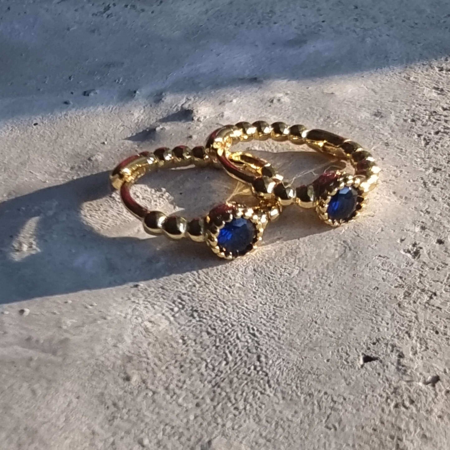 Close-up of 18K gold-plated sterling silver hoop earrings with deep blue zirconia, highlighting the dainty size and fine craftsmanship.