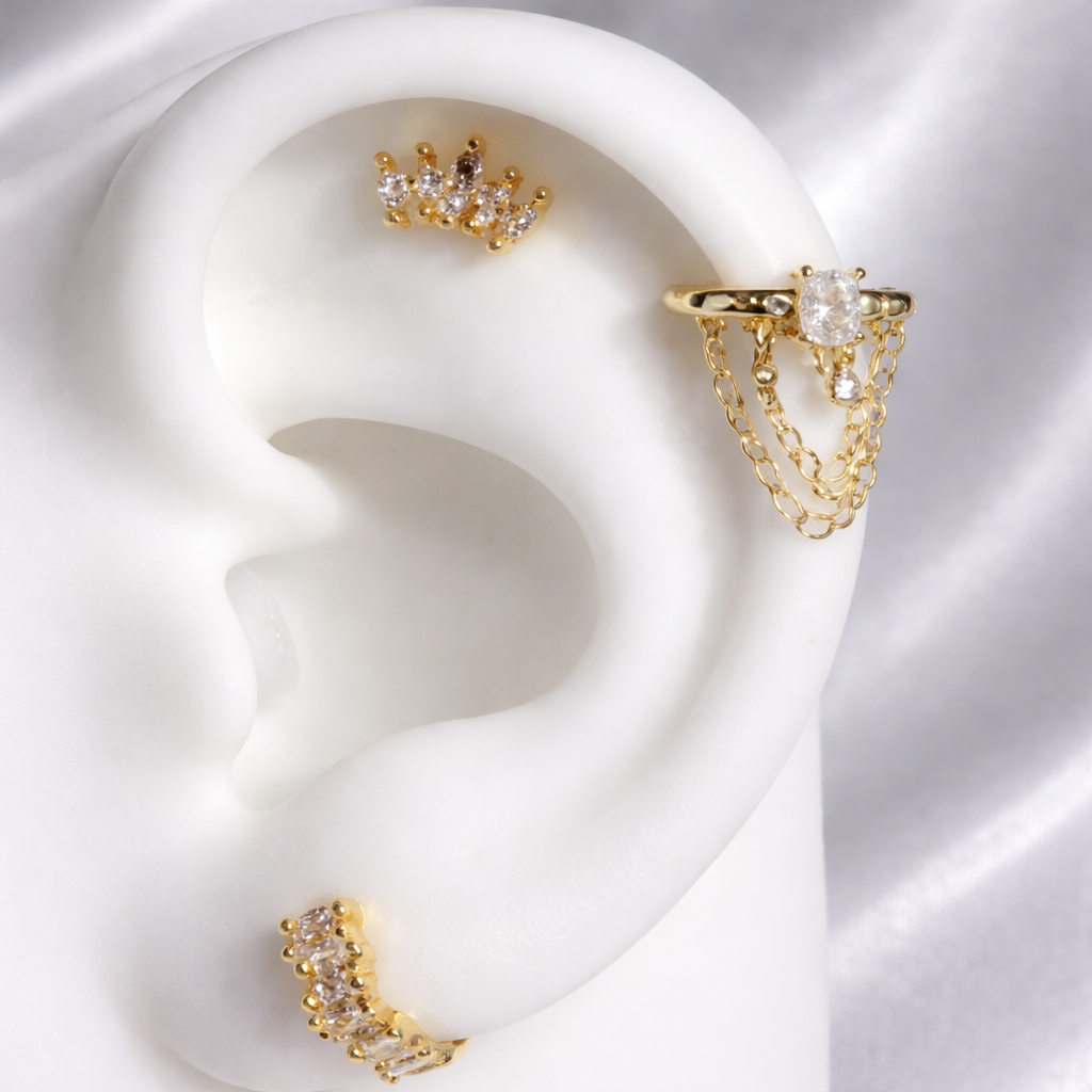 Gold earrings displayed on a white ear model with a soft white background