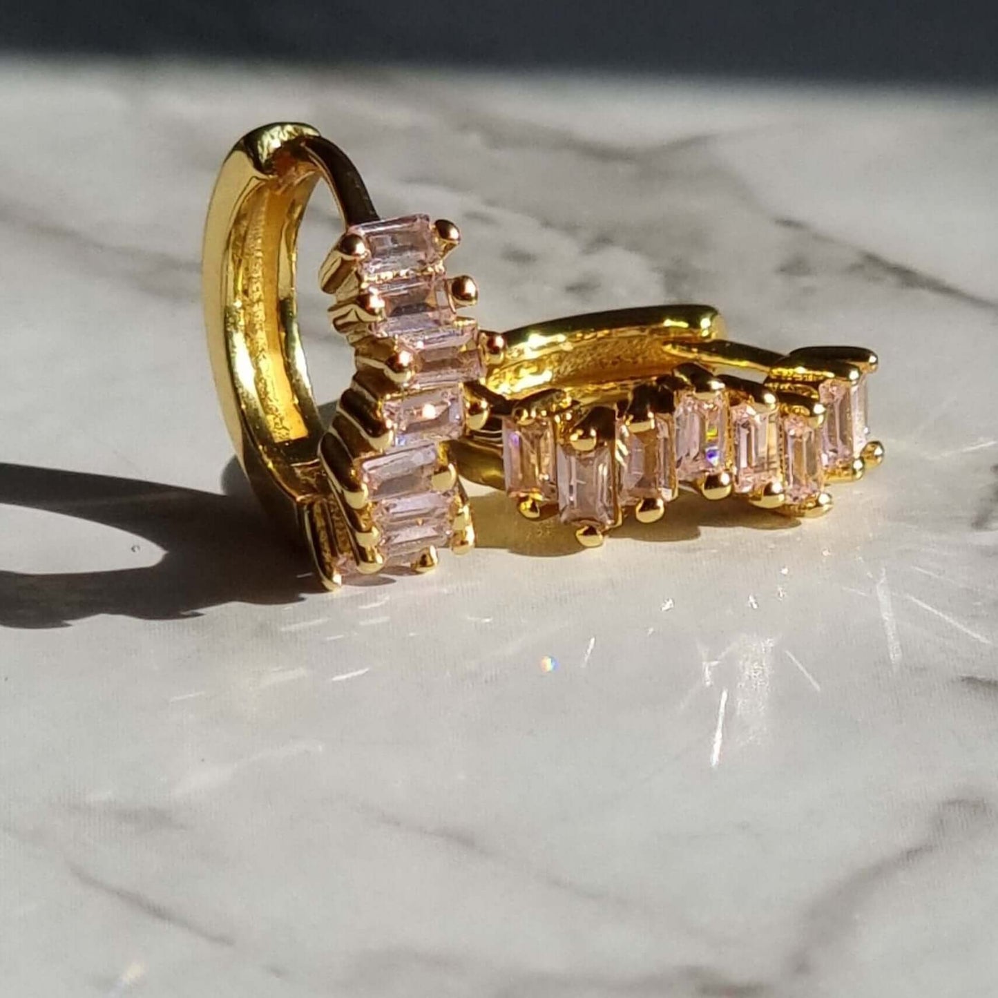 Side view of pink zirconia huggie hoops crafted from 925 sterling silver with 18K gold plating, showcasing the secure hinge clasp and elegant setting.
