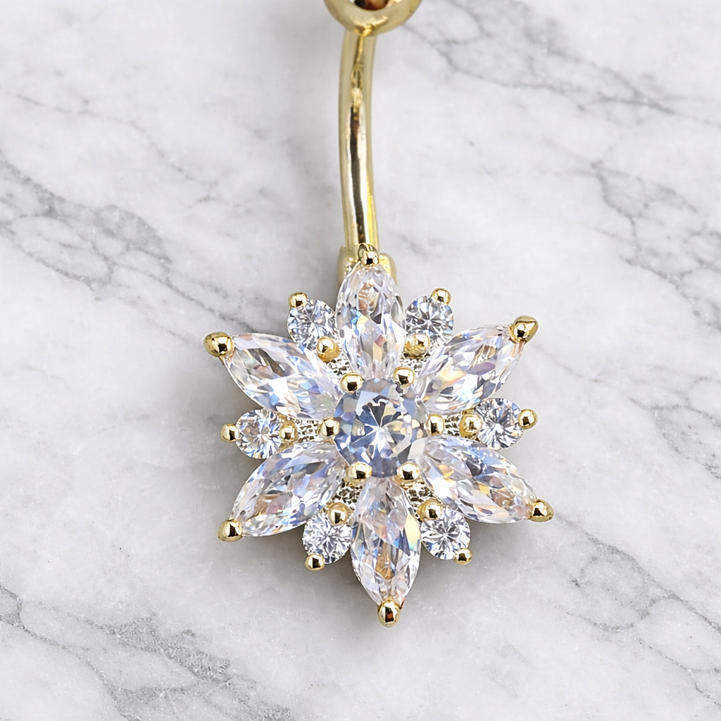 Gold belly button ring with a flower shaped clear gemstone on a marble