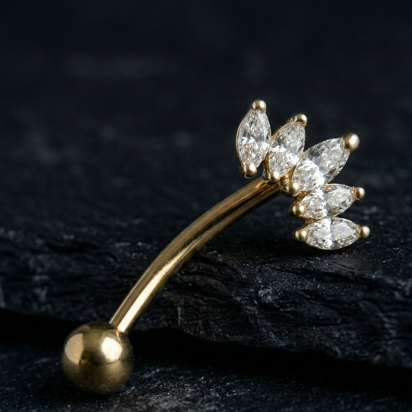Gold eyebrow/rook bar with crown diamond-like stones on a dark surface