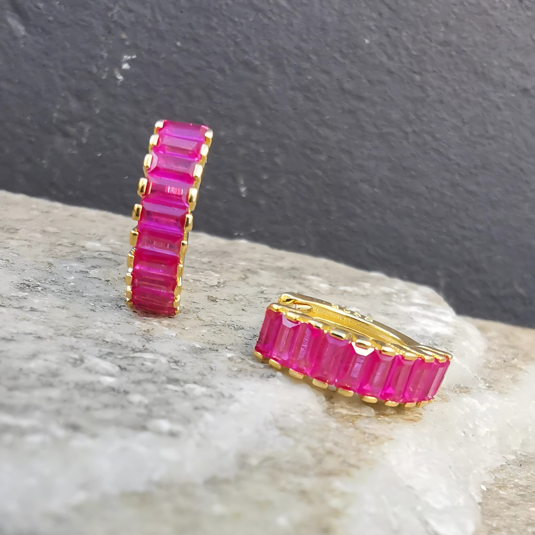 Close-up of magenta cubic zirconia huggies crafted in 925 sterling silver with 18K gold plating, showcasing rich color and refined detailing.