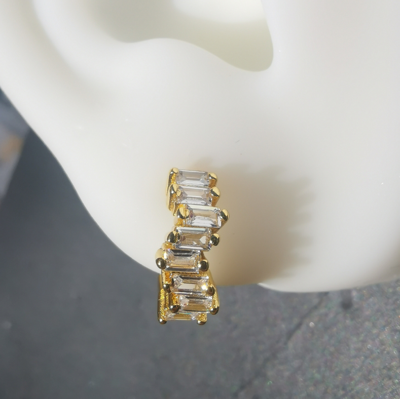 Close-up of 18K gold-plated huggie earrings with brilliant white cubic zirconia, crafted from 925 sterling silver and designed for elegant ear styling.