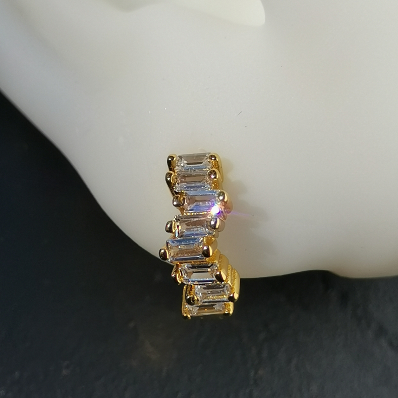 Side view of white zirconia huggie hoops in 18K gold-plated sterling silver, showing secure hinged closure and radiant stone detail.