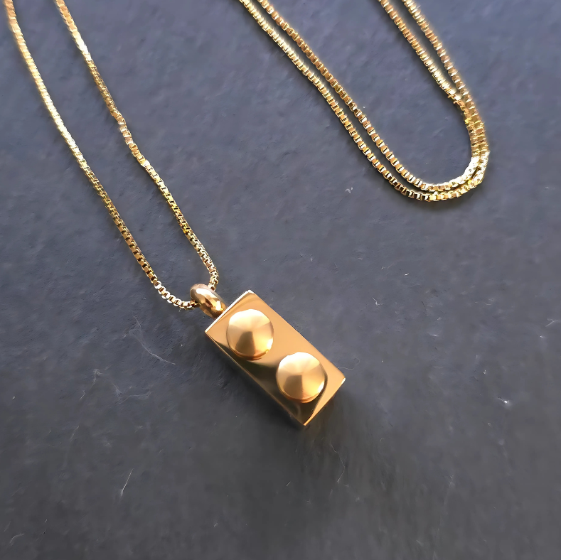 Gold Lego Brick Pendant Necklace – Stylish and unique, this 18K gold PVD plated stainless steel necklace showcases a minimalist Lego rectangle brick design. Resistant to water and sweat, making it perfect for any occasion.