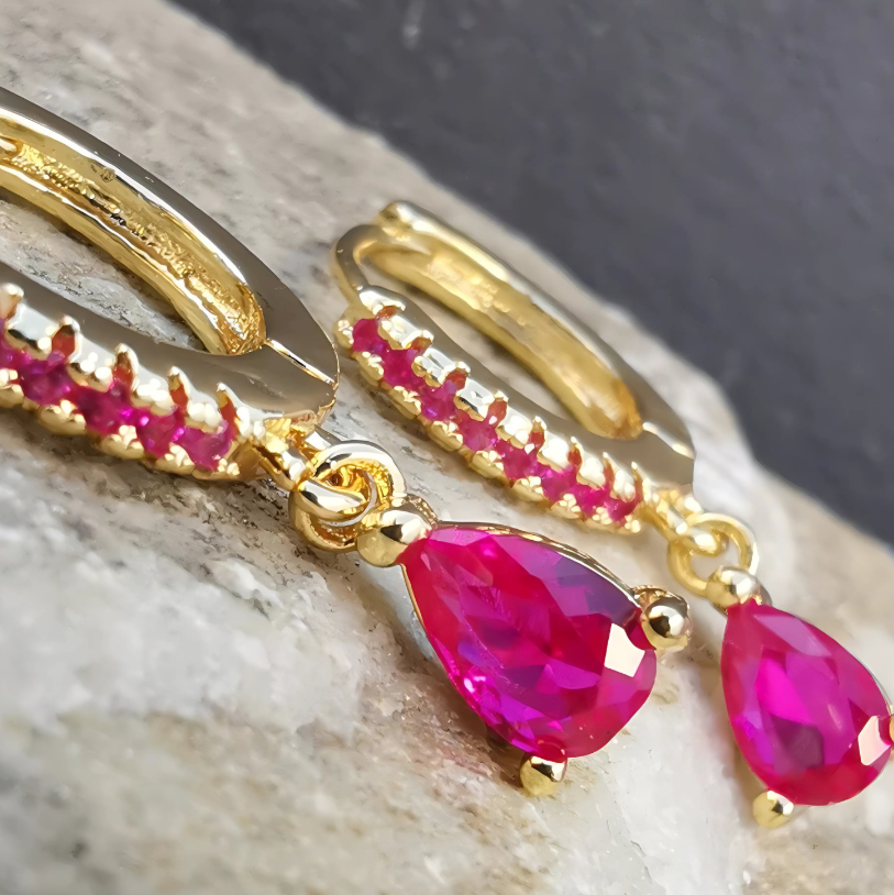 Statement droplet earrings featuring rich magenta stones in high-shine gold-filled stainless steel.