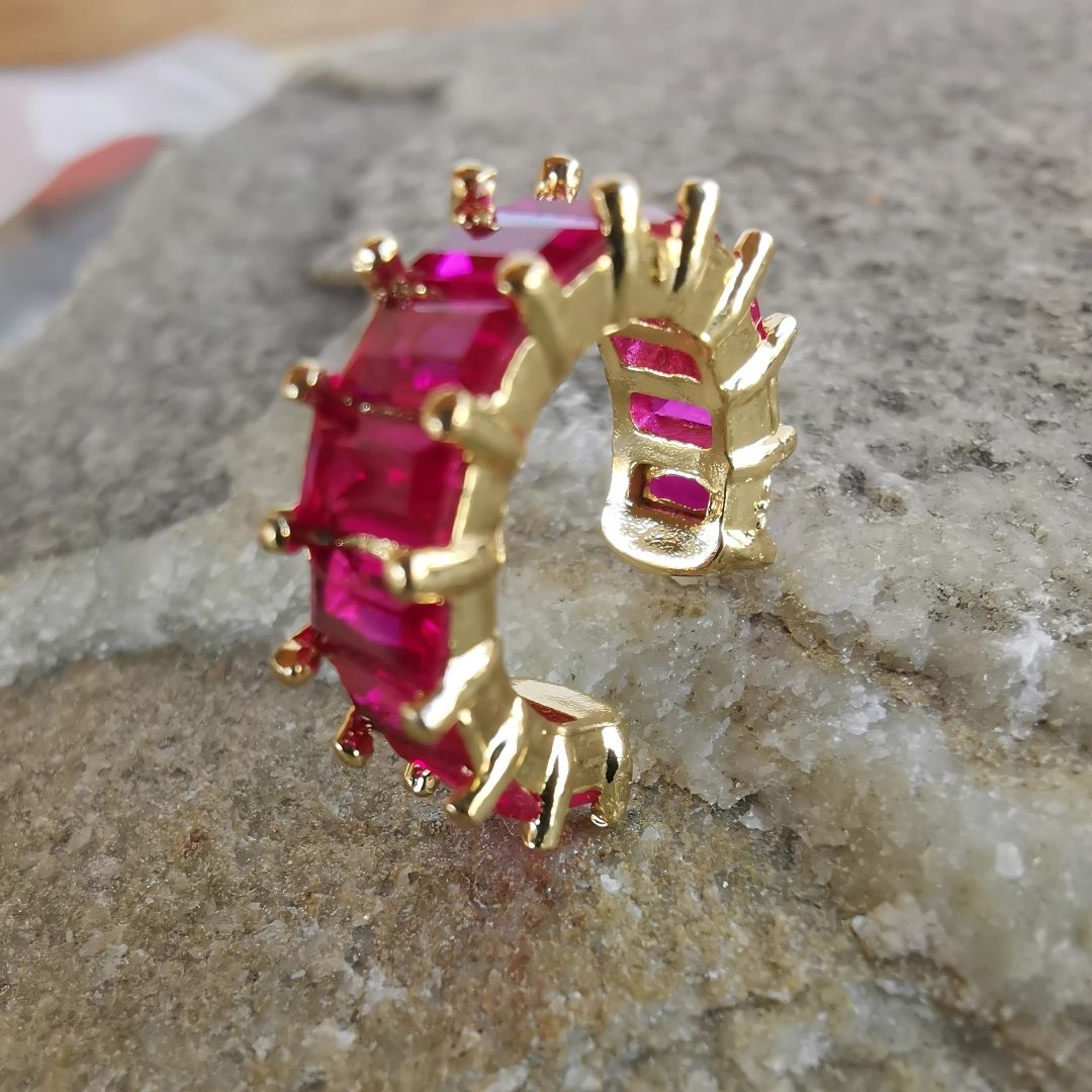 Close-up of 18K gold-plated conch ear cuff with bold magenta gemstone, made from copper and designed to wrap around the ear without a piercing.
