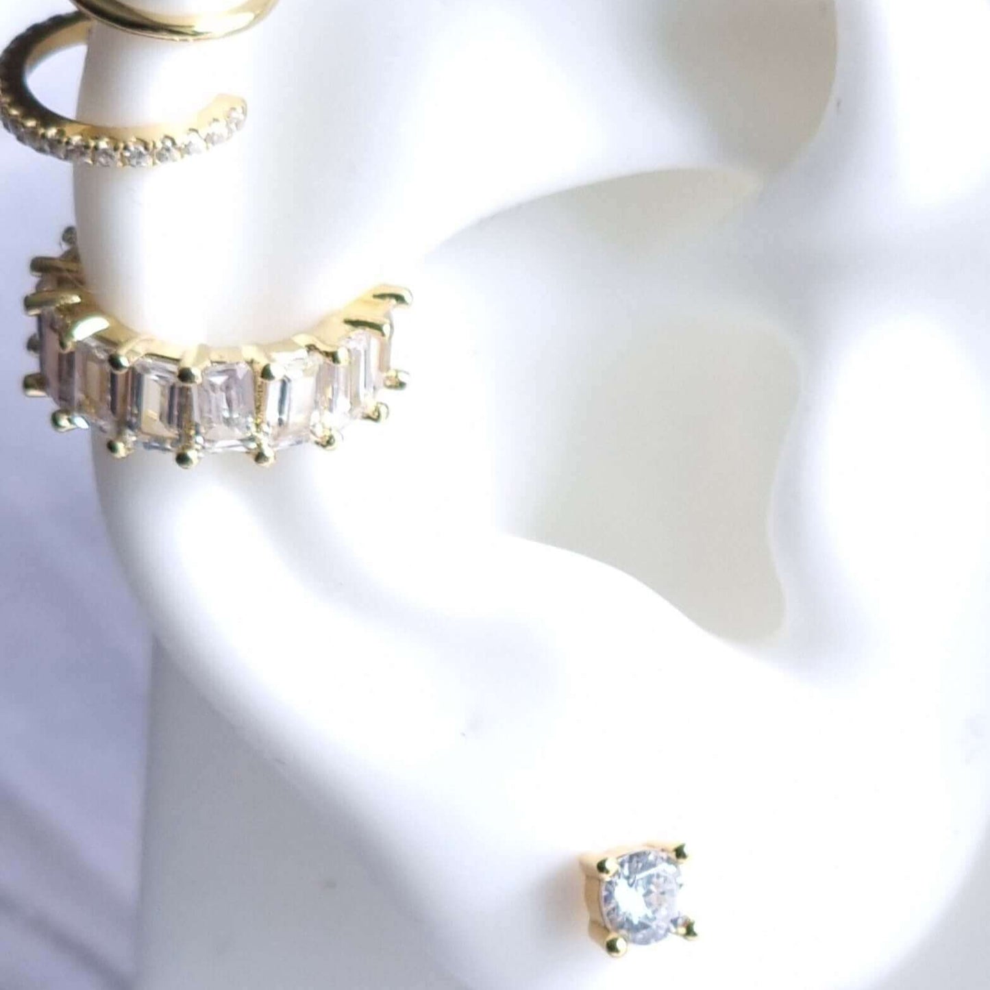 Close-up of gold conch ear cuff with clear gemstone, crafted from lightweight 18K gold-plated copper, designed to hug the ear without a piercing.