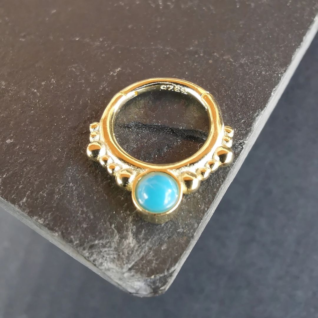 Premium piercing jewelry with a striking daith ring design, accented by a captivating turquoise stone.