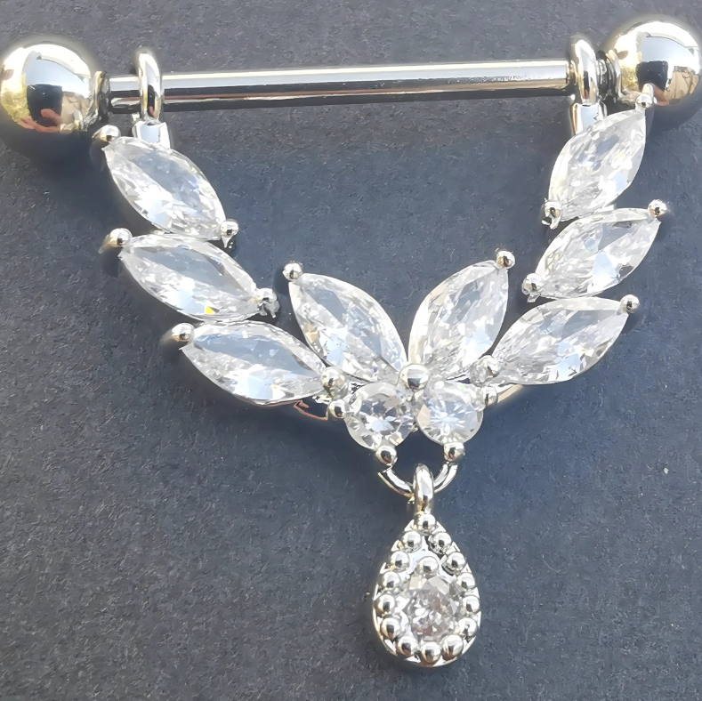 Intricate shield motif on a 316L stainless steel nipple bar highlighted by shimmering cubic zirconia accents.