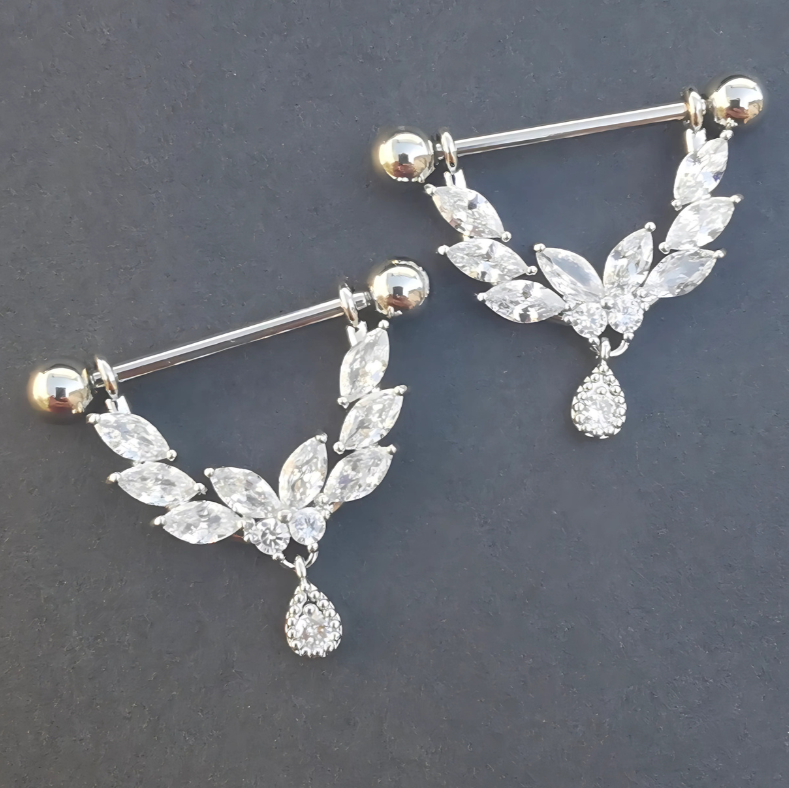 Silver shield dangle on a surgical steel nipple barbell featuring edges encrusted with sparkling cubic zirconia gems.