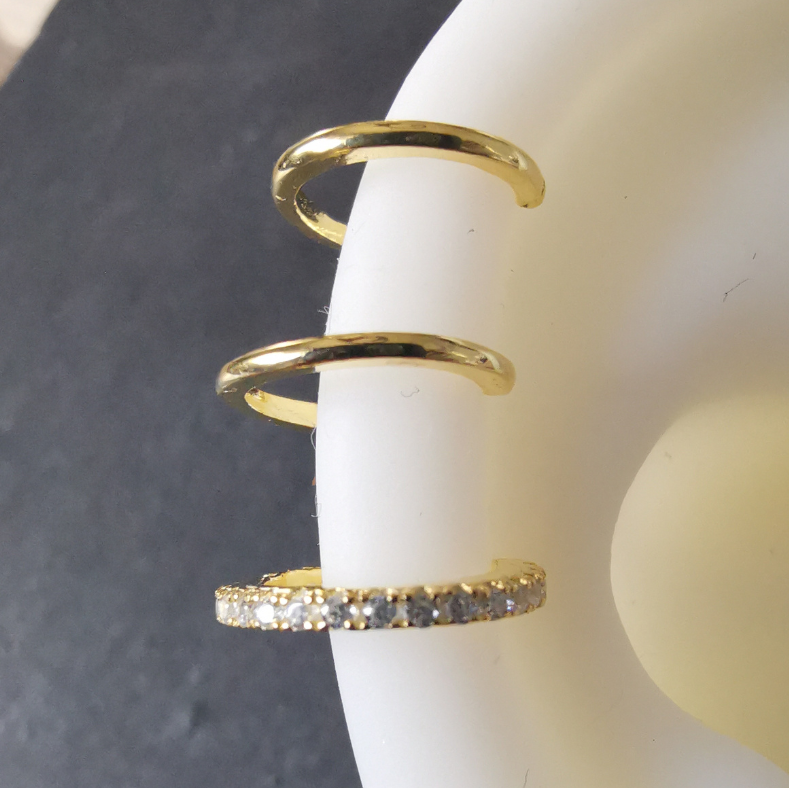 Close-up view of an 18K gold plated triple hoop ear cuff in 925 sterling silver, showcasing sleek curves and modern geometric detailing.