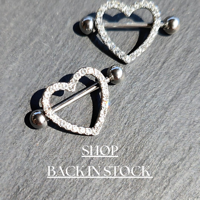 Display of bestselling body jewelry styles back in stock, including gold and silver nipple and navel piercings with sparkling gemstones.