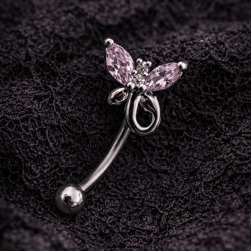 Butterfly-shaped eyebrow/rook barbell with pink gemstone on a dark textured background
