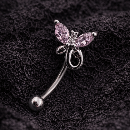 Butterfly-shaped eyebrow/rook barbell with pink gemstone on a dark textured background