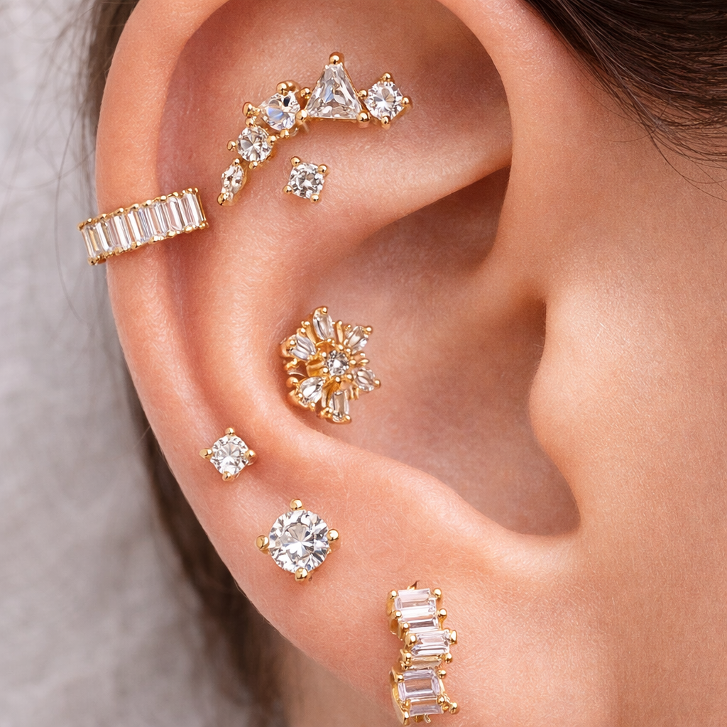 Close-up of an ear wearing multiple gold and diamond earrings.