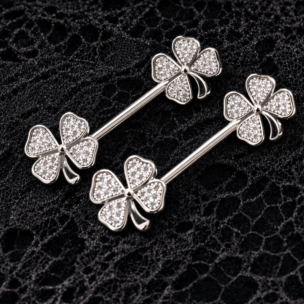 Silver four-leaf clover nipple bars on a textured black background