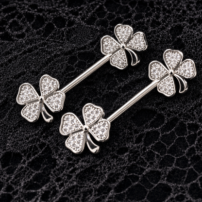 Silver four-leaf clover nipple bars on a textured black background
