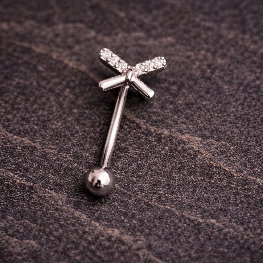 Silver eyebrow/rook bar with bow design on a textured brown surface