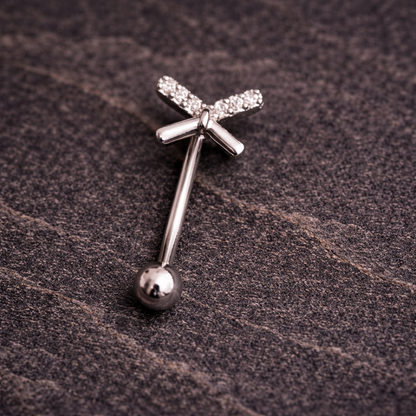 Silver eyebrow/rook bar with bow design on a textured brown surface