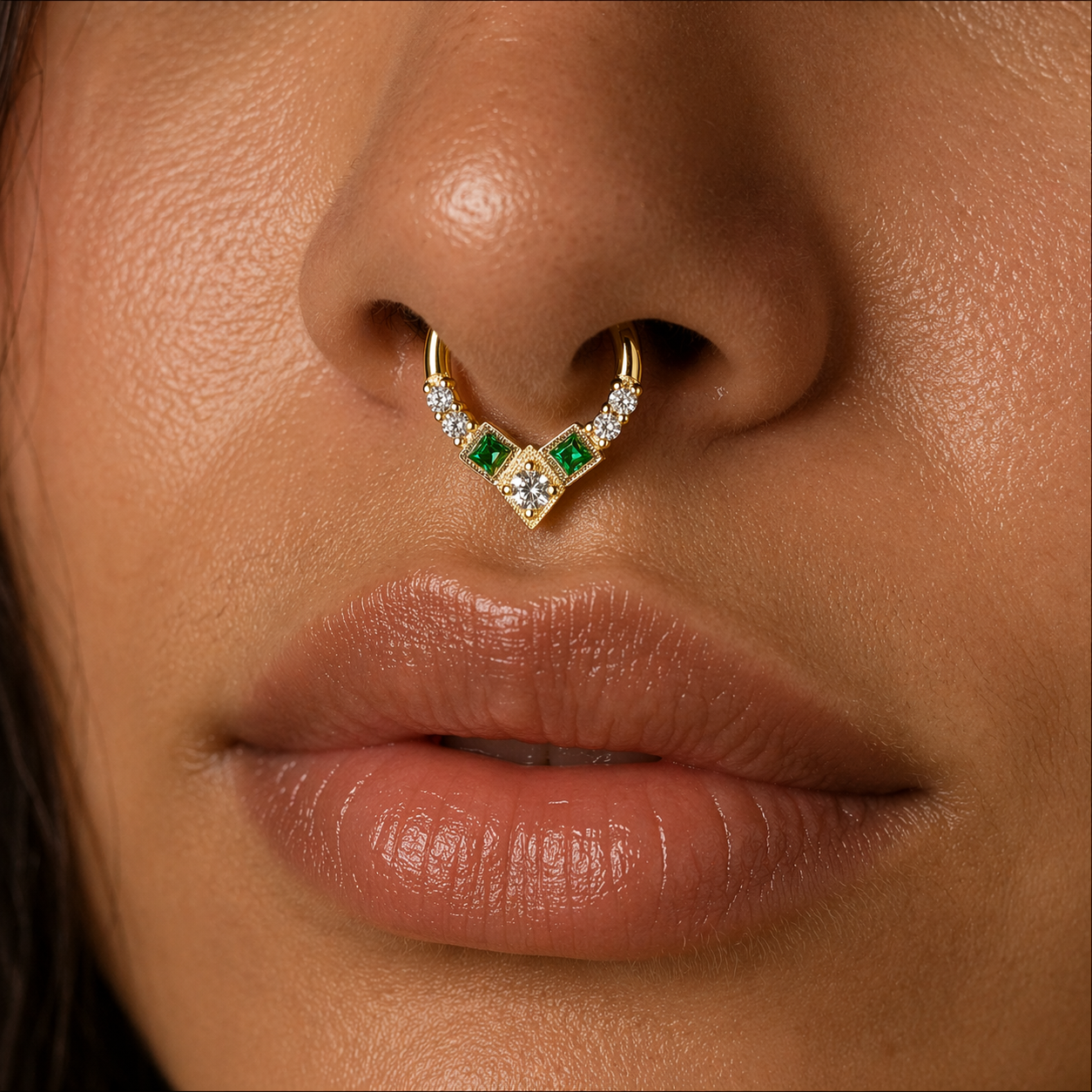 Close-up of a person wearing a gold and green gemstone nose ring.