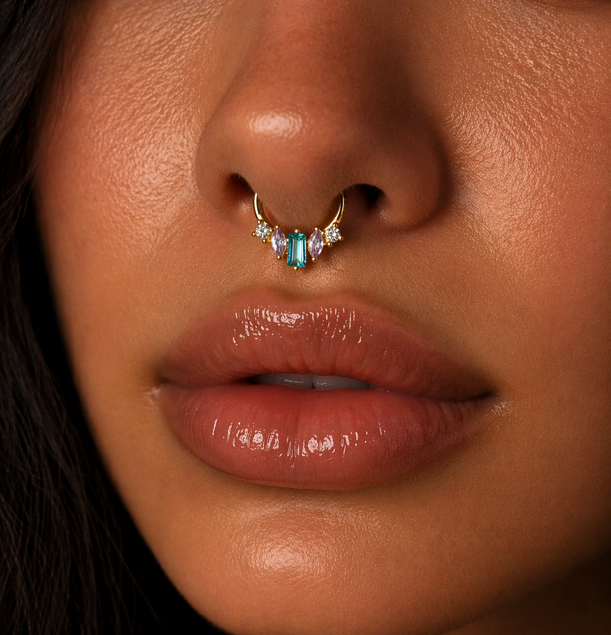 Close-up of a person wearing a gold nose ring with gemstones.