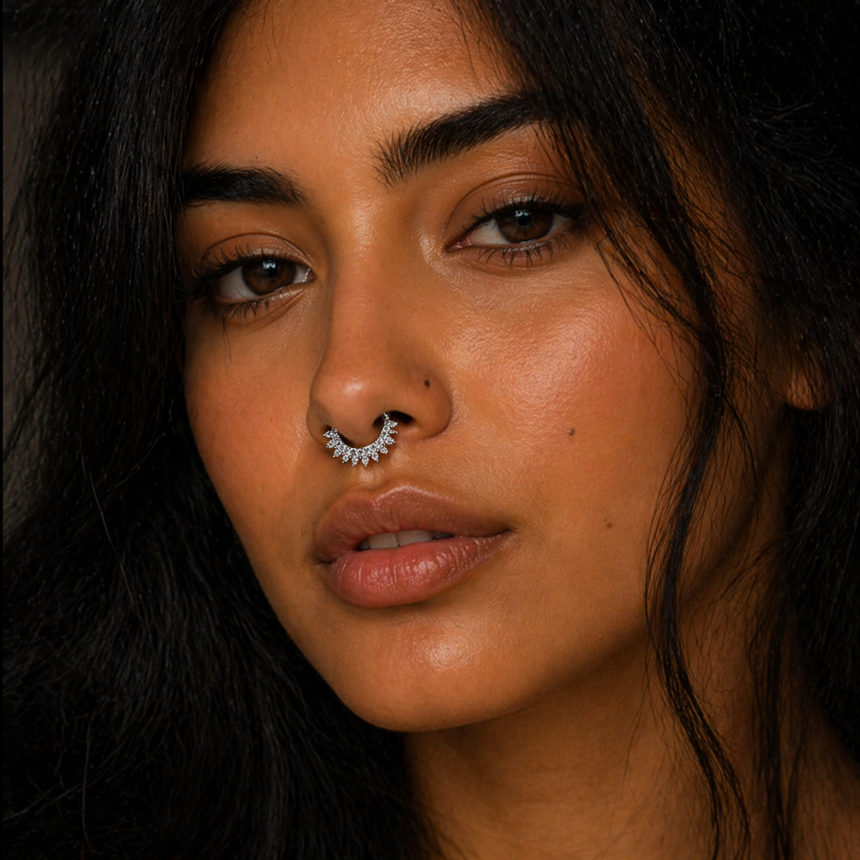 Close-up of a woman with a nose ring against a dark background
