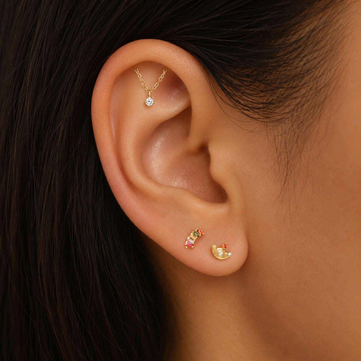 Close-up of an ear wearing gold earrings with gemstones.