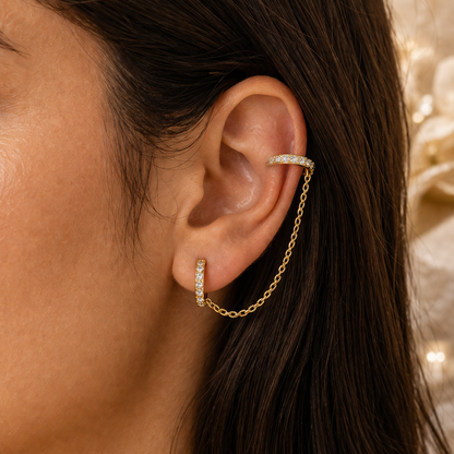 Close-up of an ear wearing gold hoop earrings with a blurred background