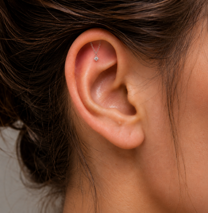 Close-up of an ear with a delicate earring against a neutral background