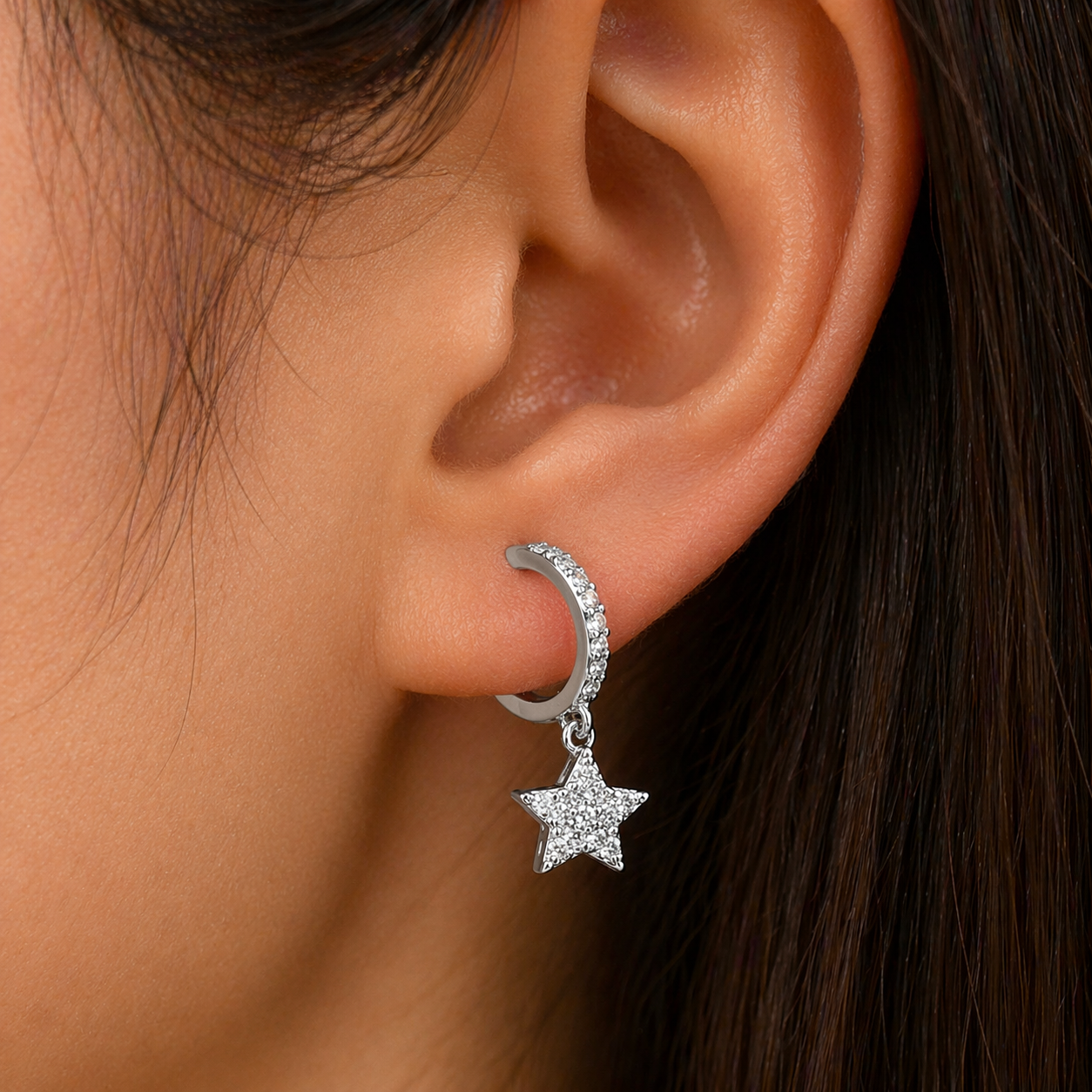 Silver earring with star detail worn by a person