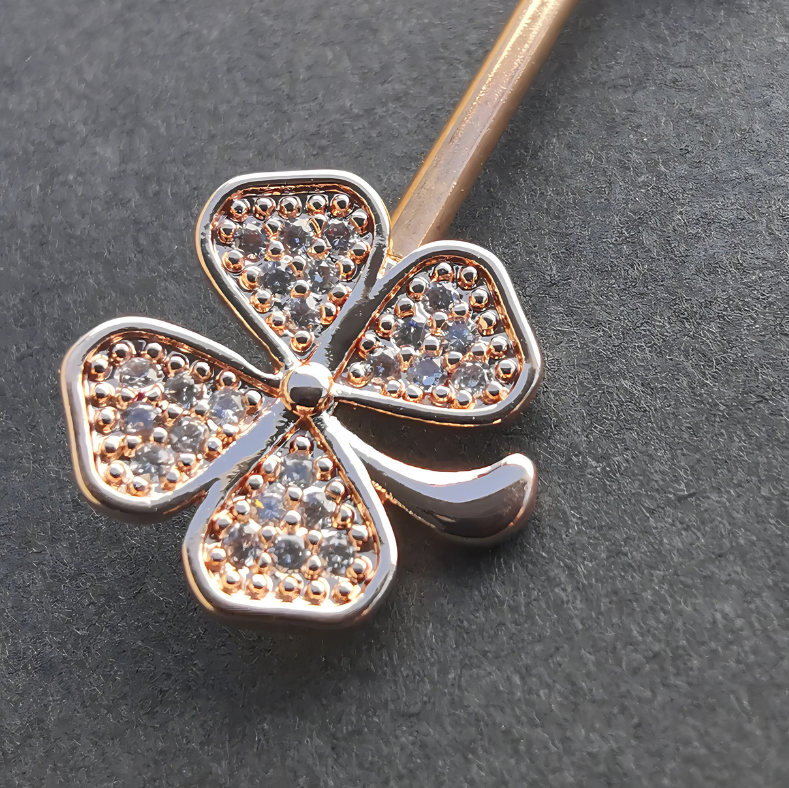 14G rose gold surgical steel nipple bar with a clover leaf design and sparkling cubic zirconia accents.
