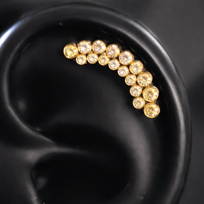 Gold earring with embedded stones on a black ear model