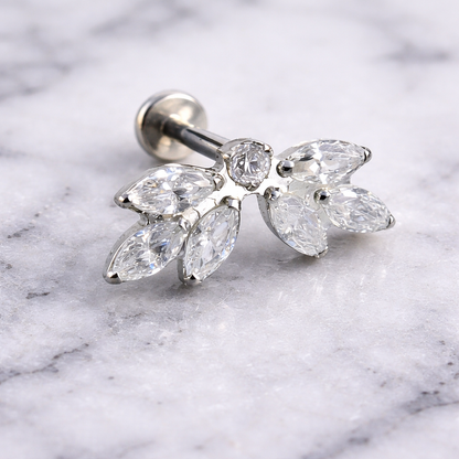 Silver earring with clear gemstones on a marble background
