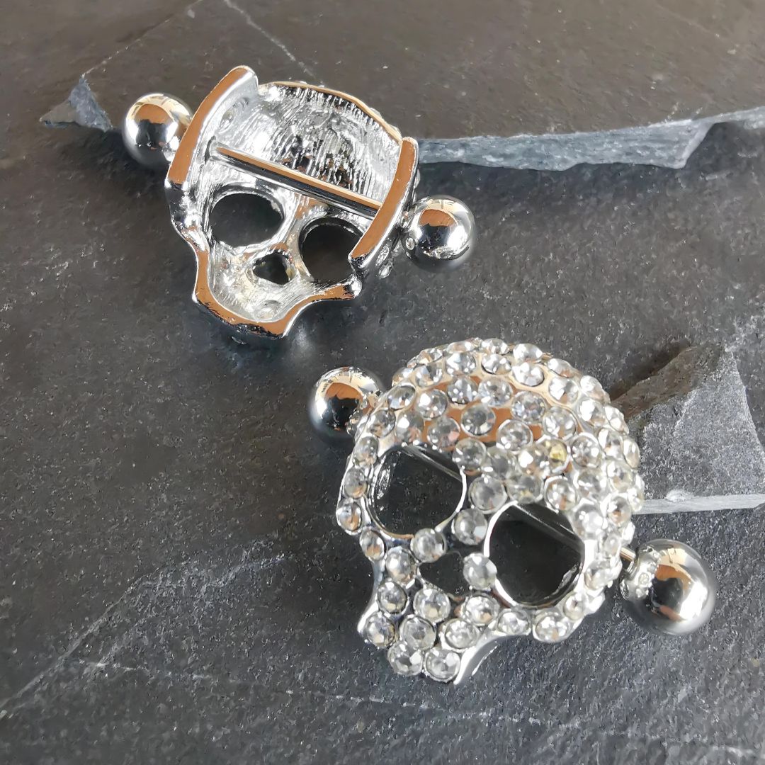 Silver skull nipple bar shields with diamond accents, made from 16G surgical steel 316L body jewelry.