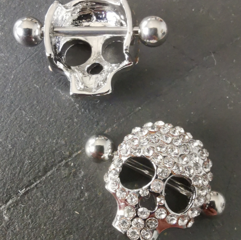 Diamond-accented skull nipple bar shields in silver, designed with 16G surgical steel 316L for body jewelry.