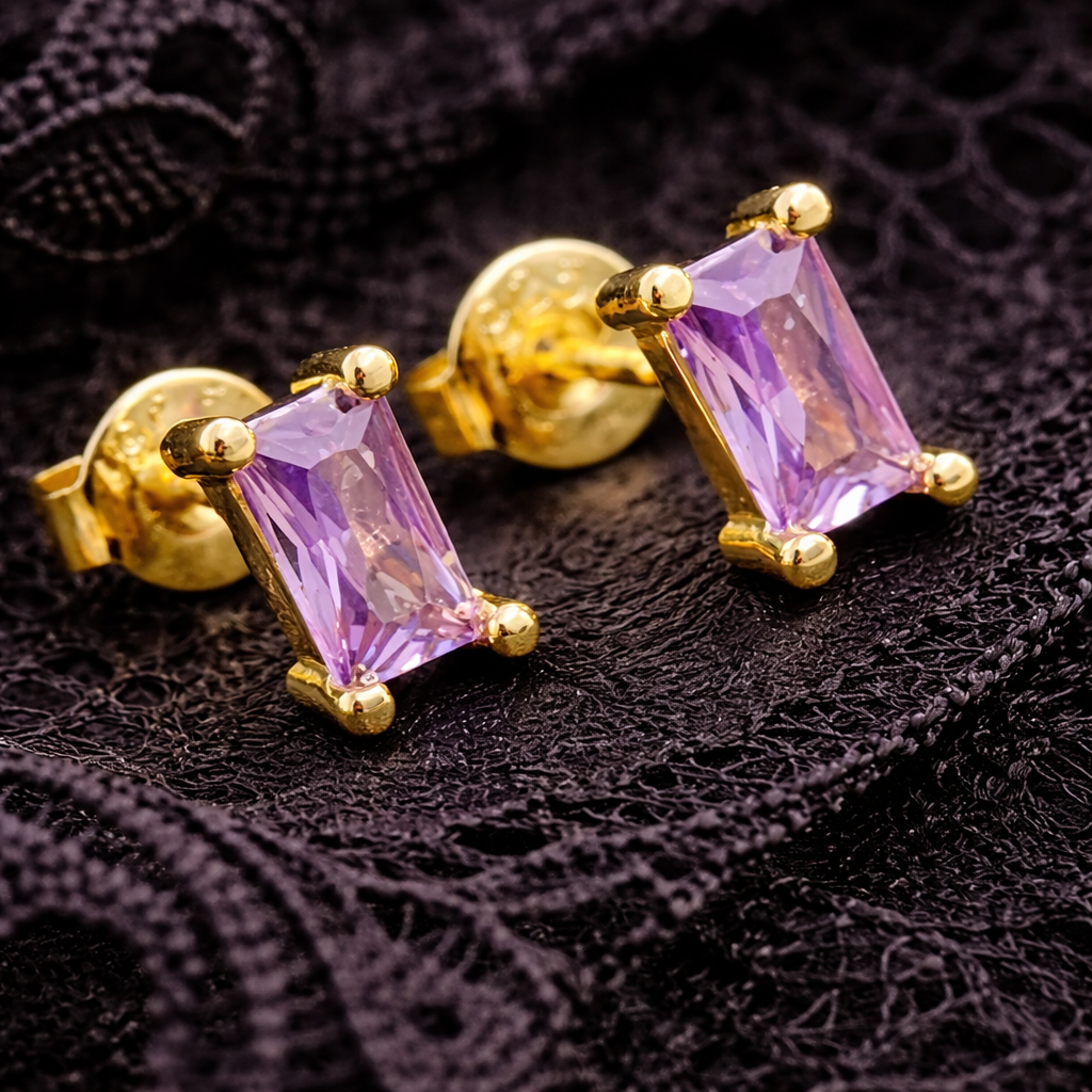 Gold earrings with purple gemstones on a black textured background