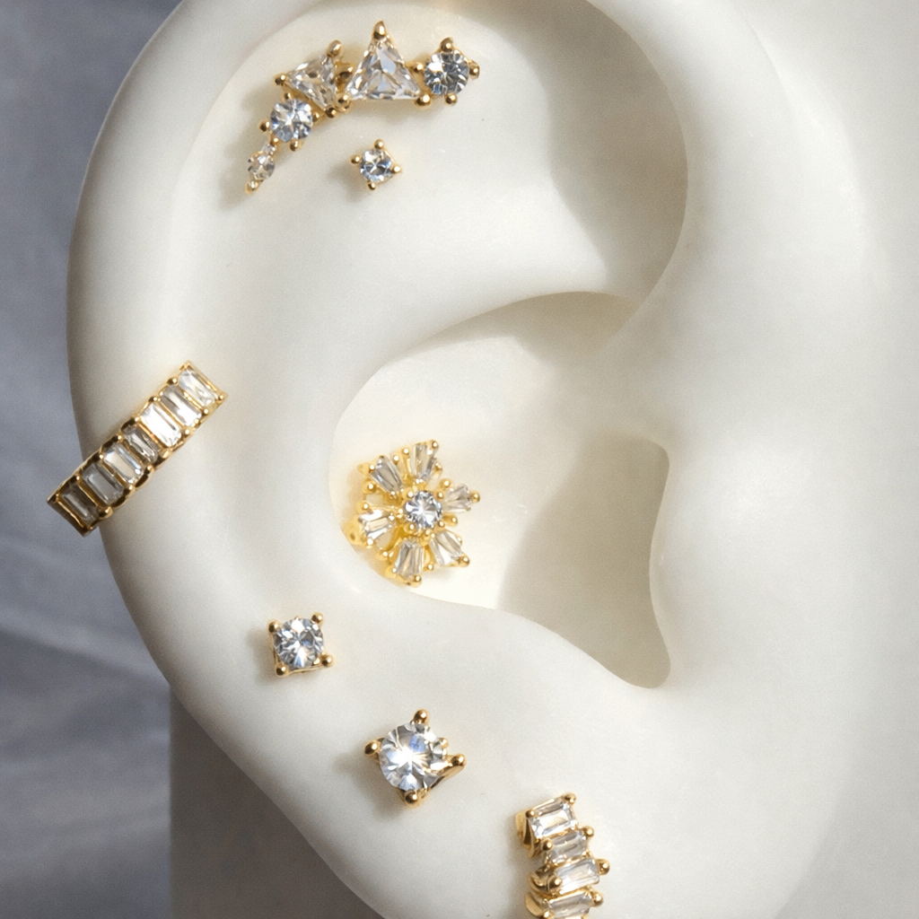 Gold and diamond earrings displayed on a white ear model.