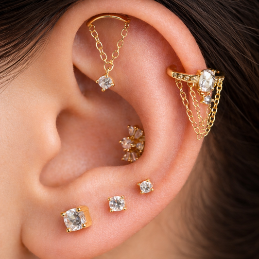 Close-up of an ear wearing gold earrings with gemstones.