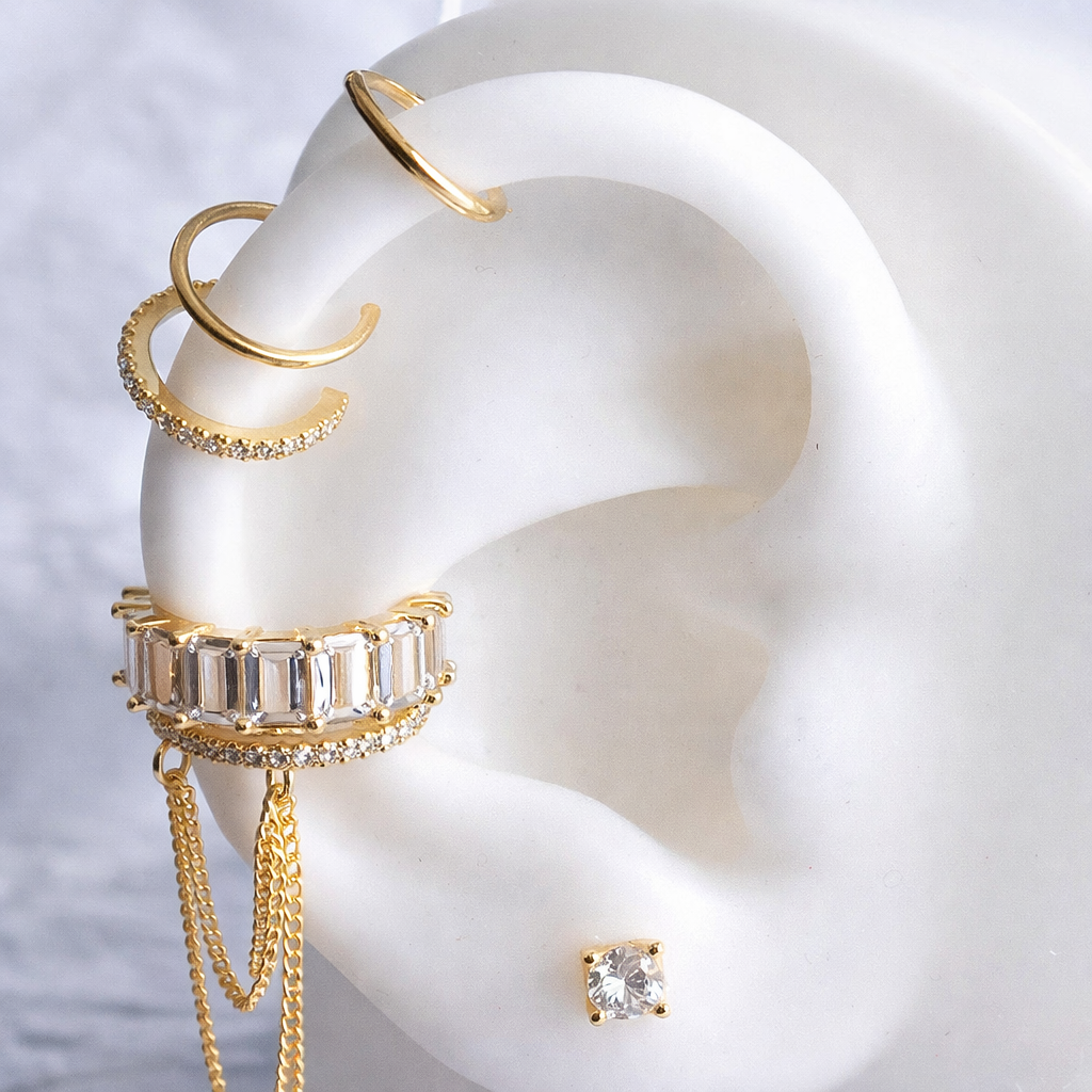Gold hoop earrings and a stud earring displayed on a white ear model.