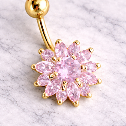 Gold belly button ring with pink gemstones on a marble background