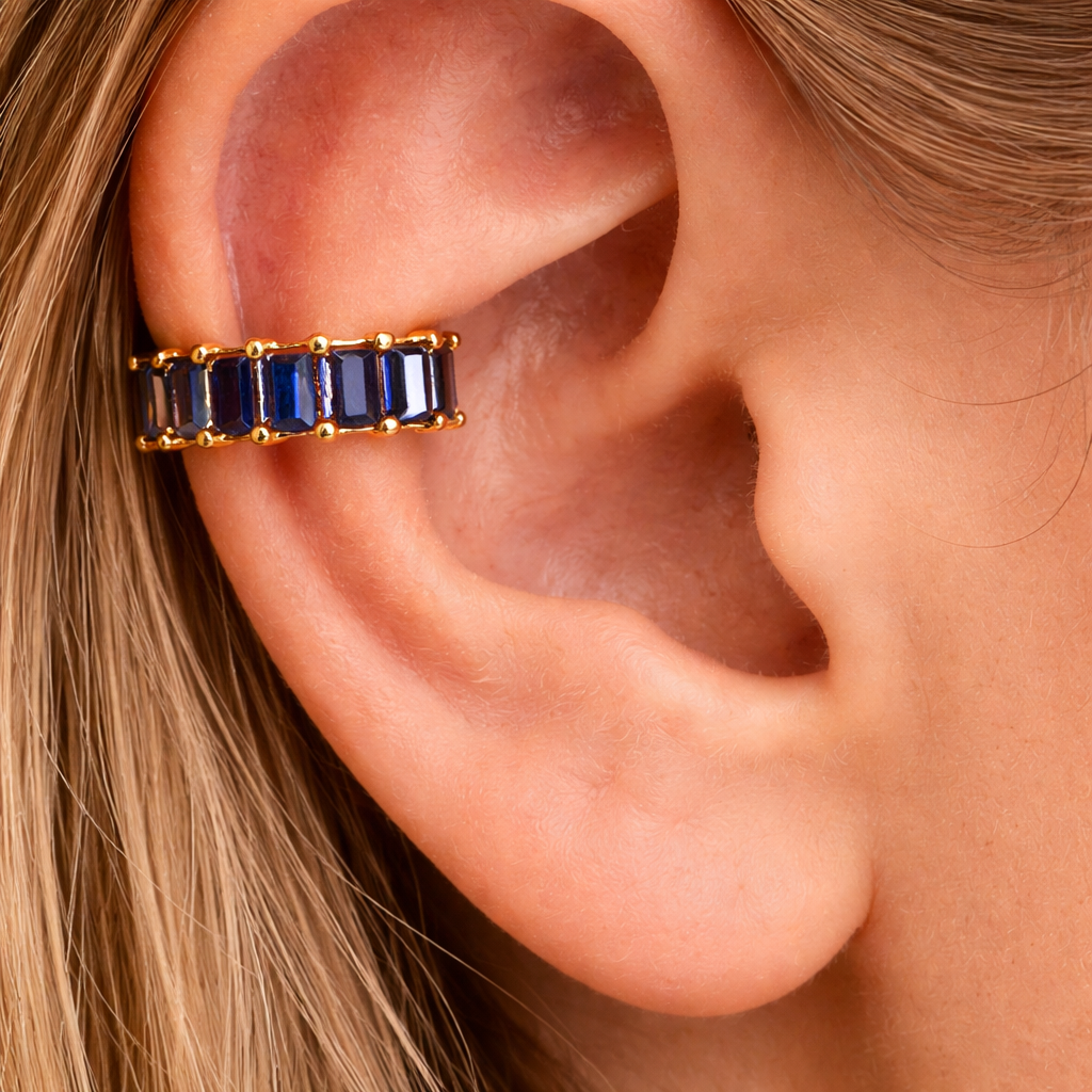 Gold earring with blue stones worn on an ear