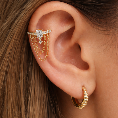 Close-up of an ear with gold earrings and a diamond ring.