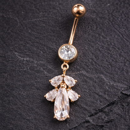 Rose Gold belly button ring with clear gemstones on a dark surface