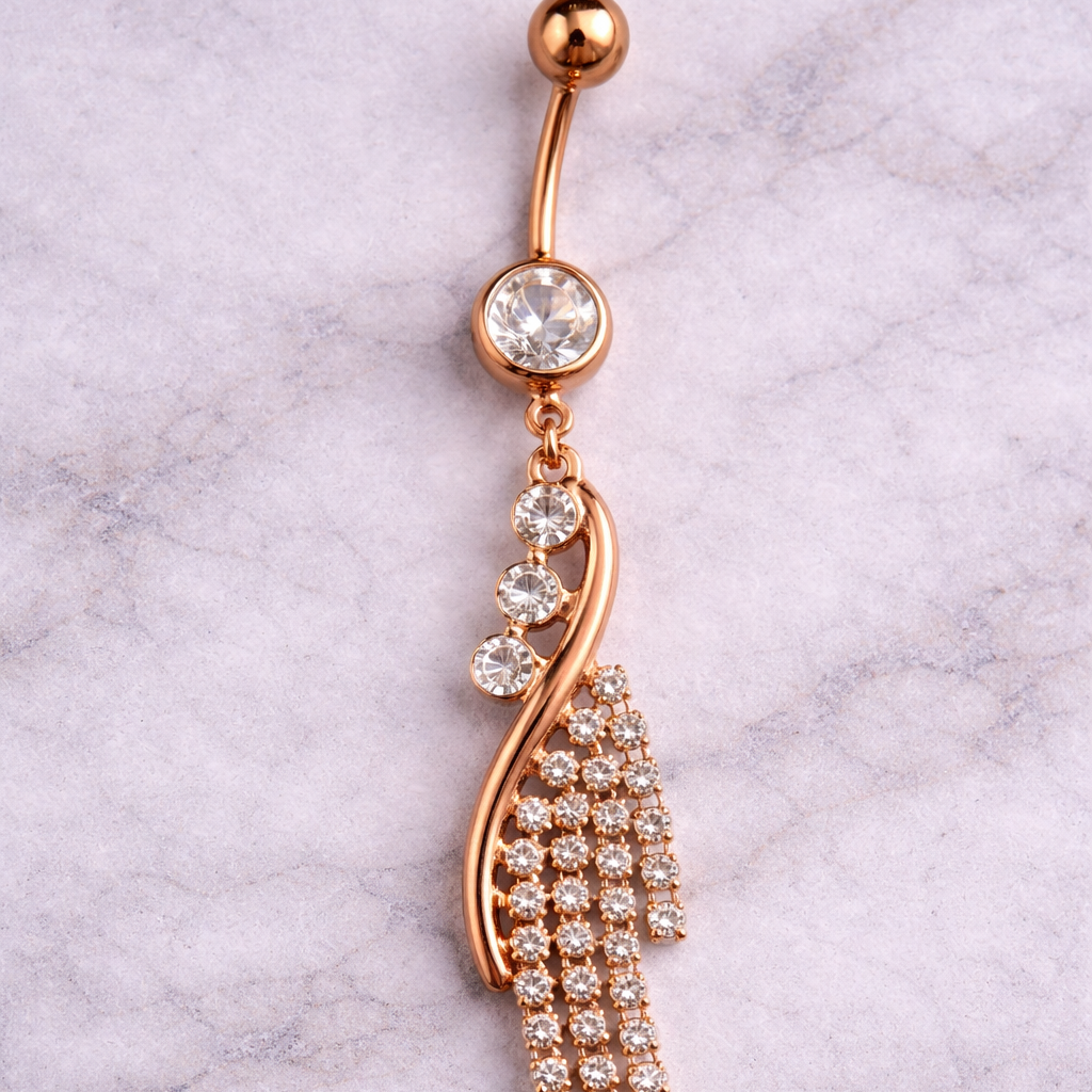 Rose gold belly button ring with crystal details on a marble background