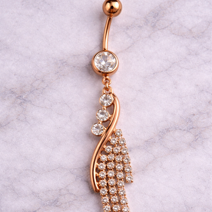 Rose gold belly button ring with crystal details on a marble background