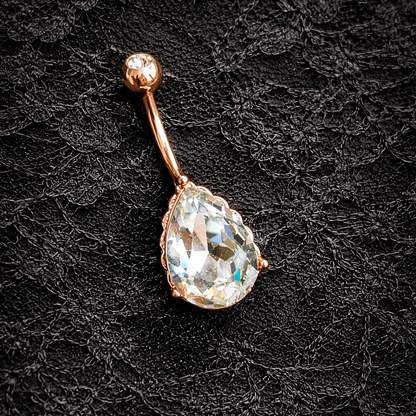 Teardrop-shaped crystal navel ring on a black lace background